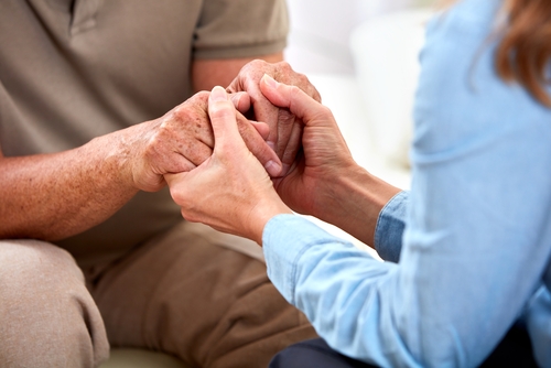 A close up shot of an elderly parent and their adult child holding hands. in-home memory care in atlanta ga